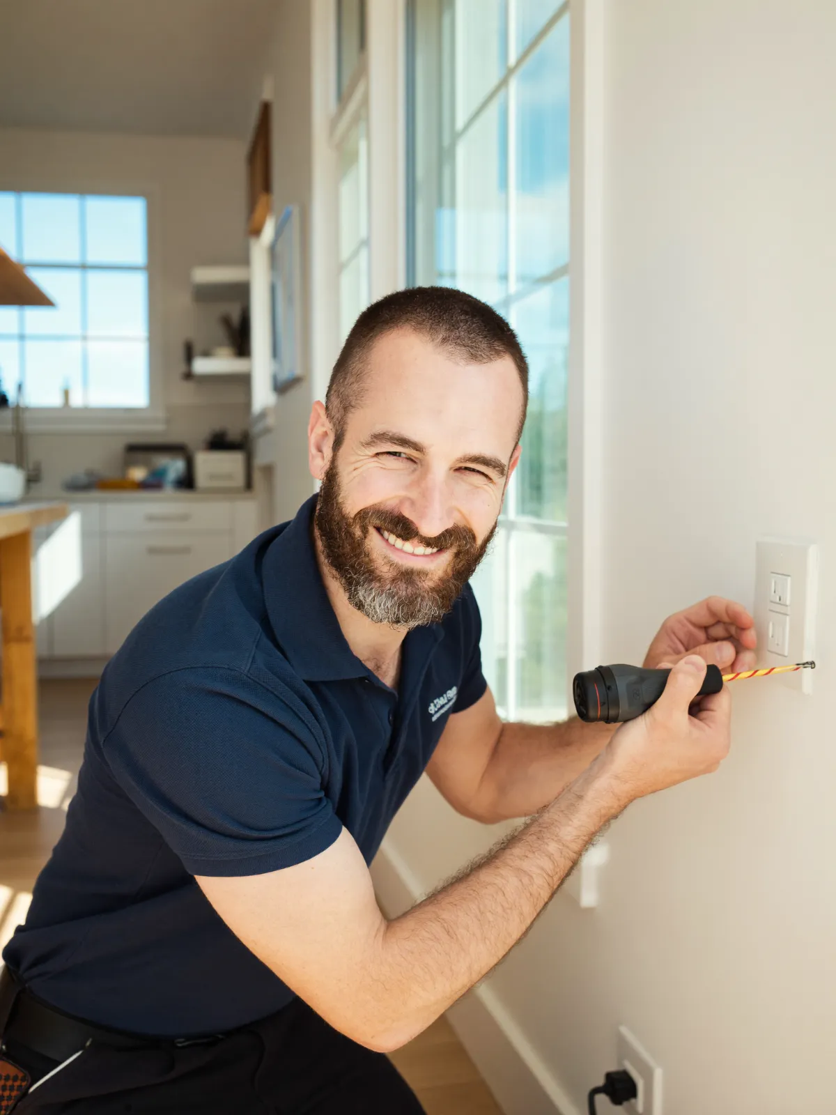 An electrician fitting a socket in a bright kitchen