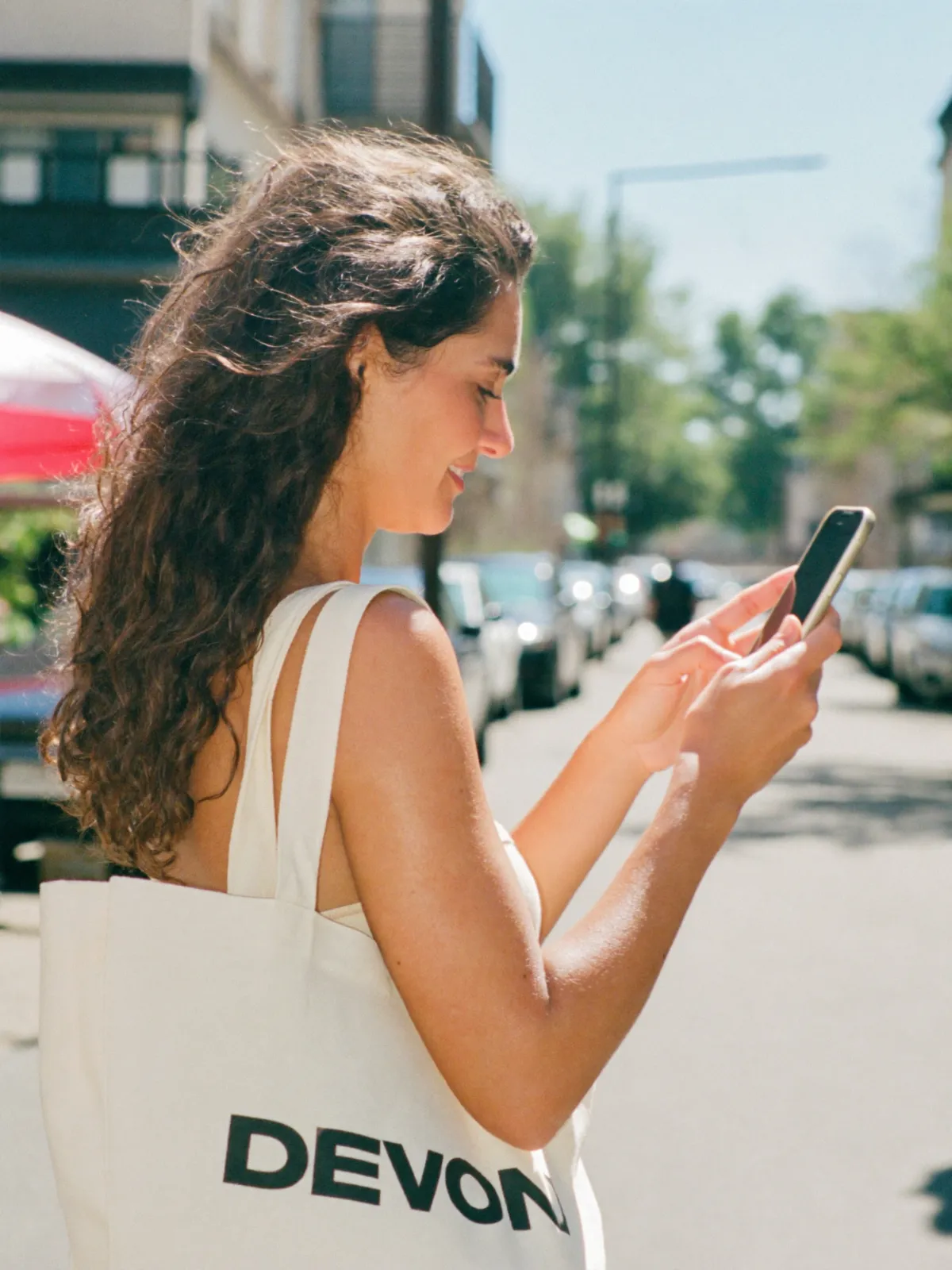 A woman reading her phone on a sunny high street