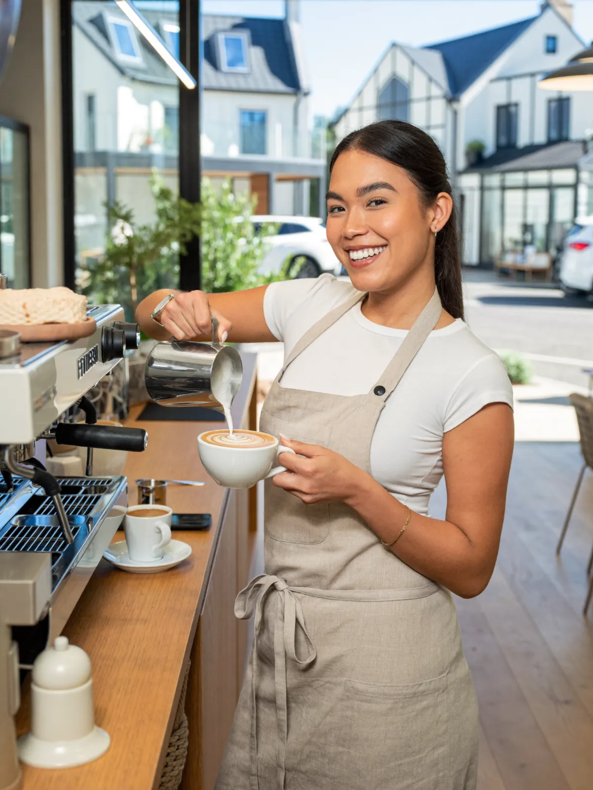 A barista pouring latte art in a bright independent coffee shop